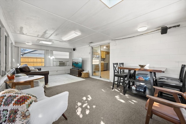 living area featuring cooling unit, concrete block wall, and carpet flooring