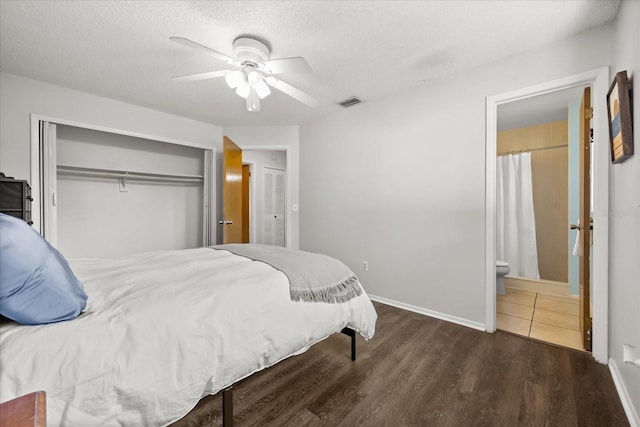 bedroom featuring wood finished floors, visible vents, a closet, ensuite bathroom, and a textured ceiling