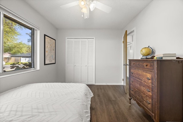 bedroom featuring dark wood finished floors, baseboards, a closet, and ceiling fan