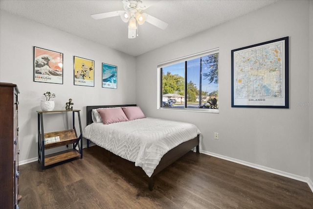 bedroom featuring baseboards, a textured ceiling, and wood finished floors