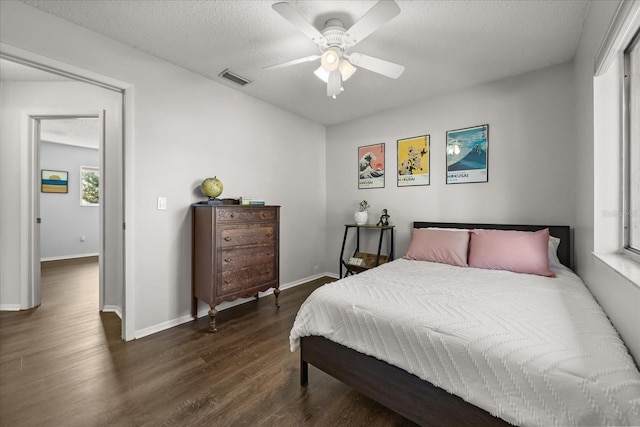 bedroom with visible vents, baseboards, wood finished floors, a textured ceiling, and a ceiling fan