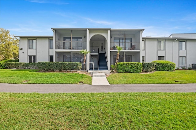 view of front of property featuring stucco siding, stairway, and a front yard