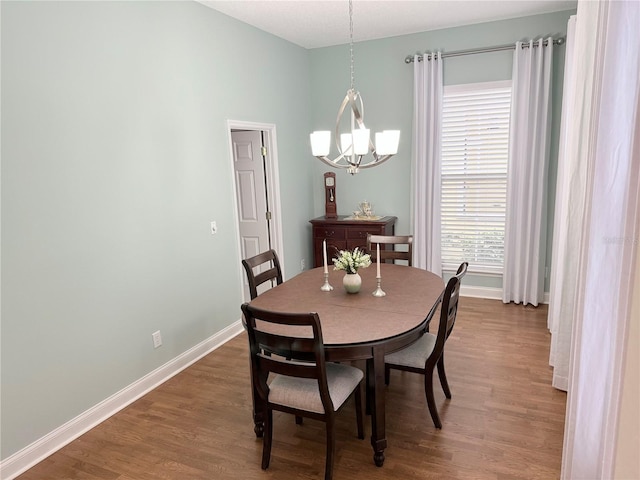 dining room featuring a chandelier, baseboards, and wood finished floors