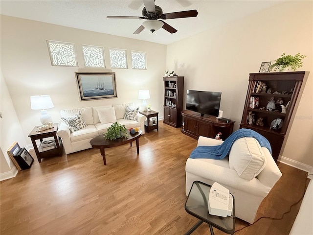 living area with wood finished floors, baseboards, and ceiling fan