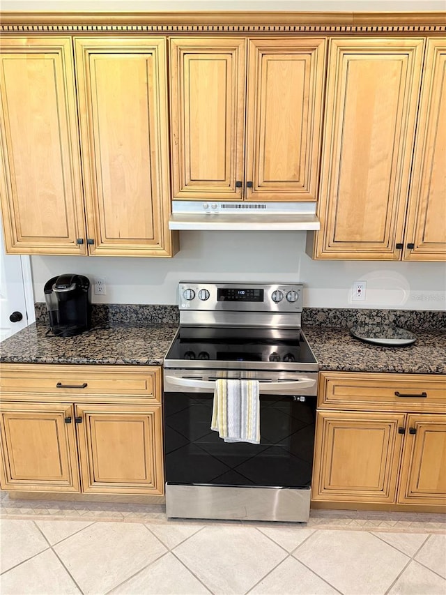 kitchen featuring dark stone counters, light tile patterned floors, stainless steel electric range, and under cabinet range hood