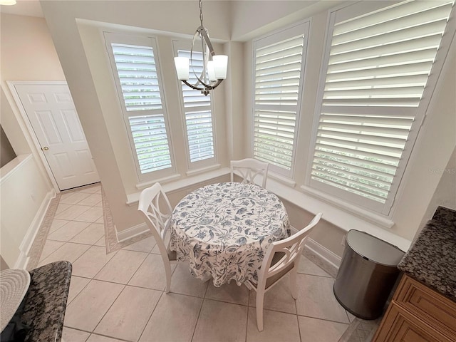 dining space with an inviting chandelier, light tile patterned flooring, and baseboards