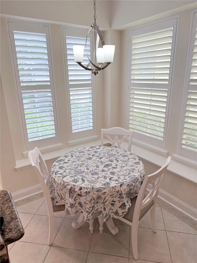 tiled dining space with a notable chandelier and baseboards