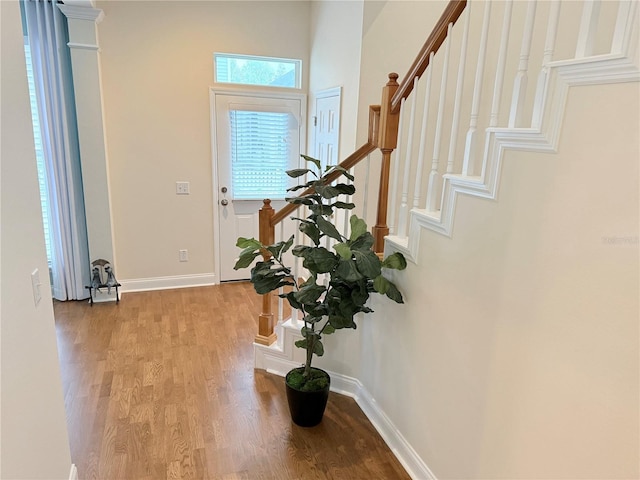 foyer entrance featuring stairway, baseboards, and light wood finished floors