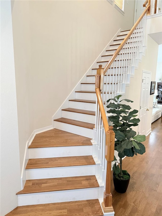 stairway with a high ceiling and wood finished floors