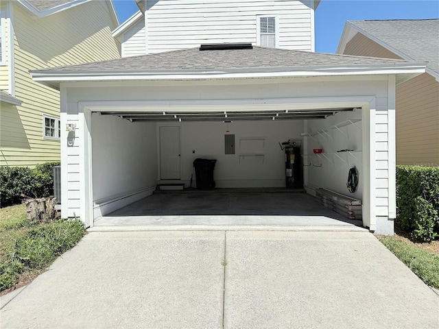 garage with concrete driveway, electric panel, and water heater