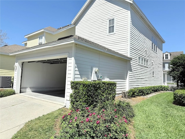 view of side of home featuring a lawn, cooling unit, and concrete driveway