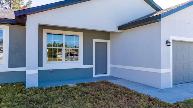 doorway to property with a garage and stucco siding