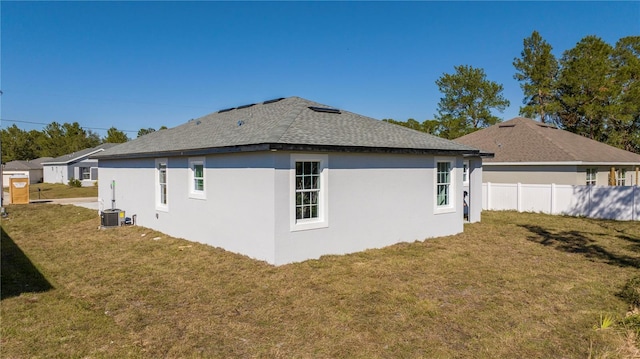 view of side of property featuring stucco siding, fence, and a lawn