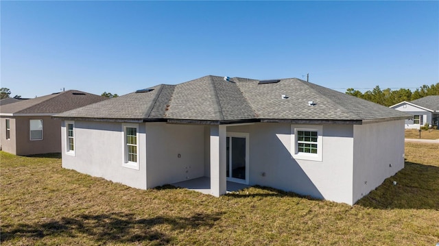 rear view of property featuring stucco siding, a lawn, and roof with shingles