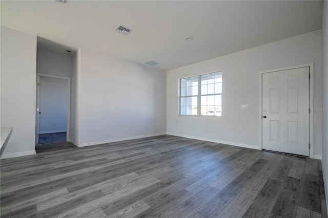 unfurnished living room featuring wood finished floors, visible vents, and baseboards