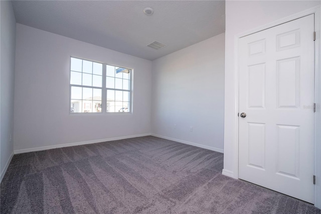 unfurnished room featuring baseboards, visible vents, and dark colored carpet