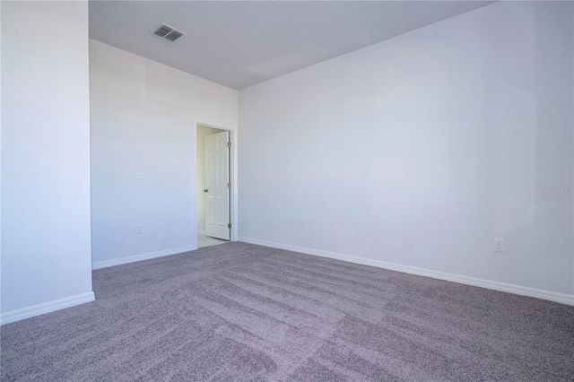 carpeted spare room with a textured ceiling, visible vents, and baseboards