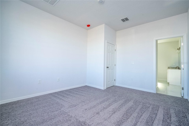 unfurnished bedroom with a textured ceiling, carpet, visible vents, and baseboards