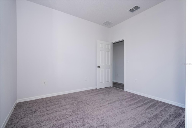 empty room with carpet flooring, visible vents, and baseboards