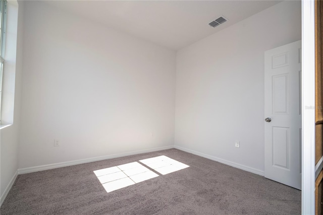 empty room with carpet floors, visible vents, and baseboards