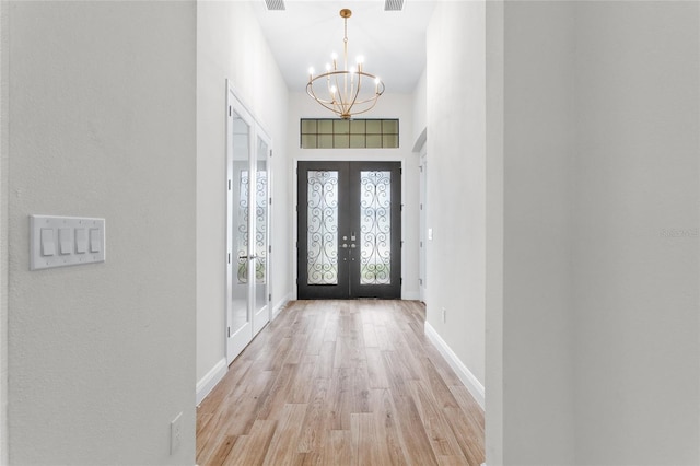 entryway with light wood-type flooring, visible vents, french doors, baseboards, and a chandelier