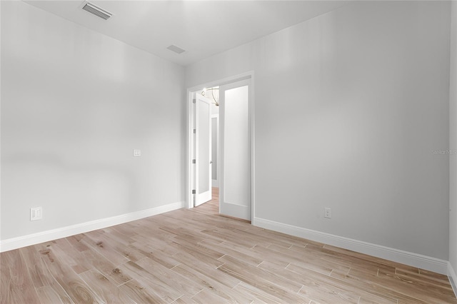 empty room with baseboards, visible vents, and light wood-style floors