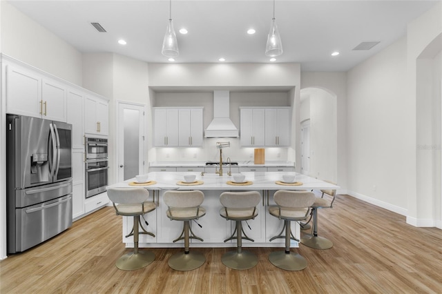 kitchen featuring arched walkways, stainless steel appliances, visible vents, and custom range hood