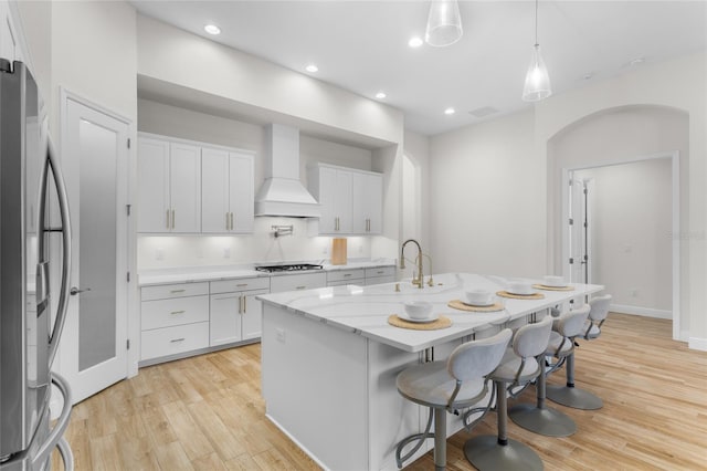 kitchen with light wood-style floors, freestanding refrigerator, custom range hood, and gas cooktop