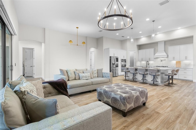 living room with arched walkways, recessed lighting, visible vents, and light wood-style floors