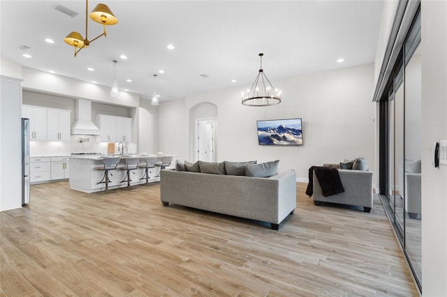 living room with arched walkways, a notable chandelier, recessed lighting, visible vents, and light wood finished floors