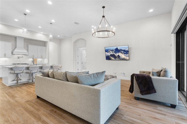 living room featuring arched walkways, light wood-type flooring, baseboards, and recessed lighting