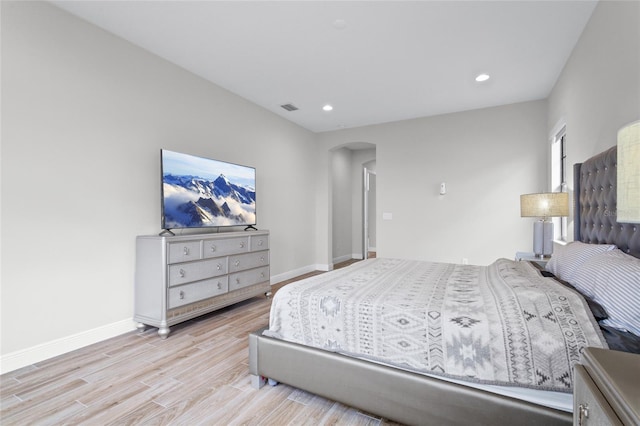 bedroom featuring arched walkways, baseboards, visible vents, and light wood-style floors