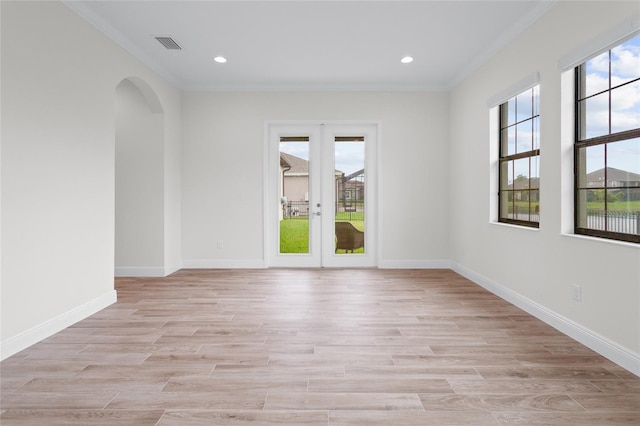 spare room with light wood-style flooring, arched walkways, a wealth of natural light, and french doors