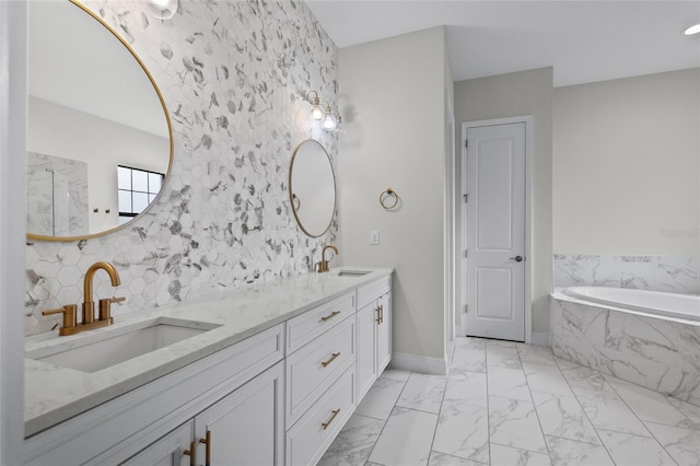 bathroom with marble finish floor, a sink, baseboards, and a bath