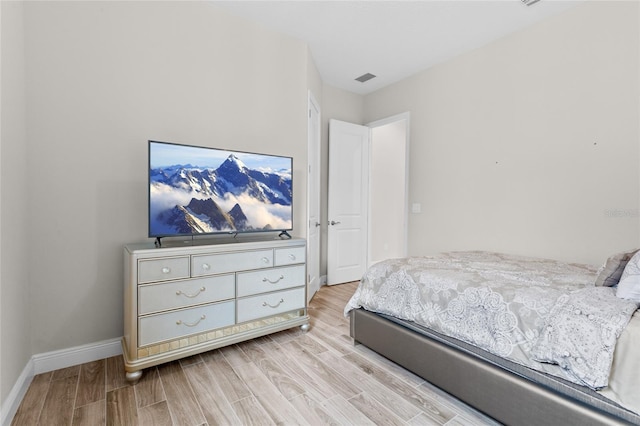 bedroom with visible vents, baseboards, and wood finished floors