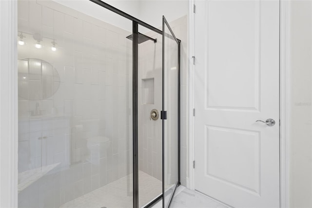 bathroom with marble finish floor and a shower stall