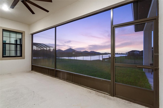 unfurnished sunroom featuring a water view, a healthy amount of sunlight, and ceiling fan