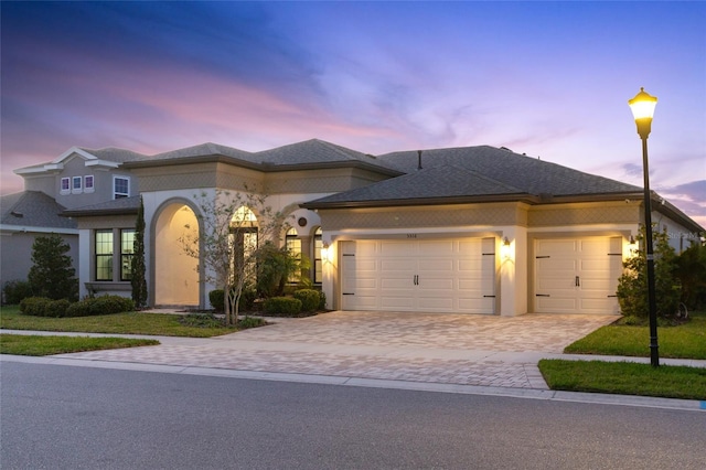 view of front facade featuring decorative driveway, an attached garage, and stucco siding