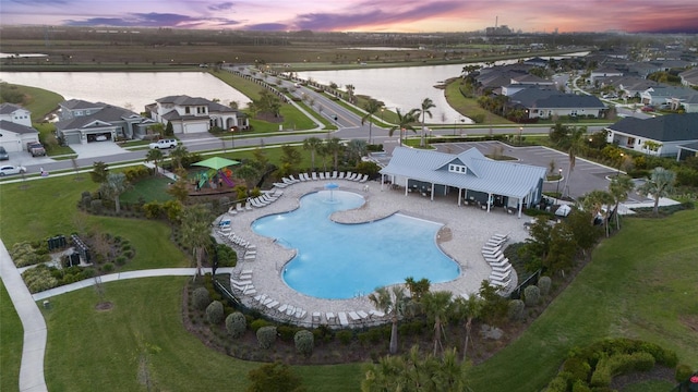 aerial view at dusk featuring a water view and a residential view