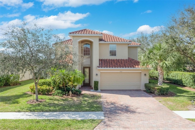 mediterranean / spanish-style home with a garage, a tile roof, decorative driveway, stucco siding, and a front lawn