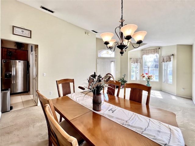 dining area featuring a chandelier, light colored carpet, visible vents, and lofted ceiling