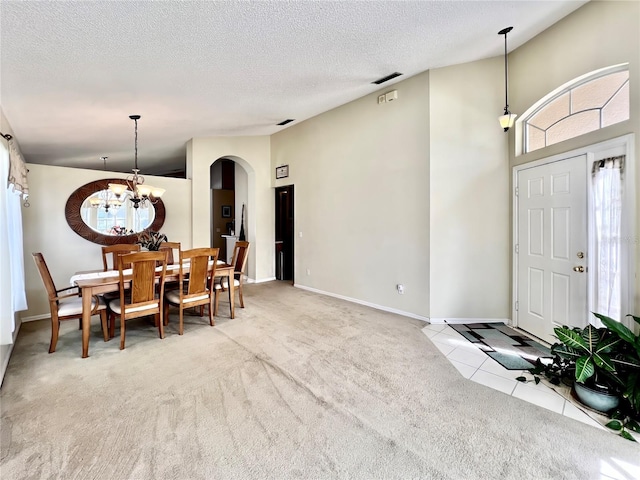 dining area with carpet floors, arched walkways, a textured ceiling, and tile patterned floors