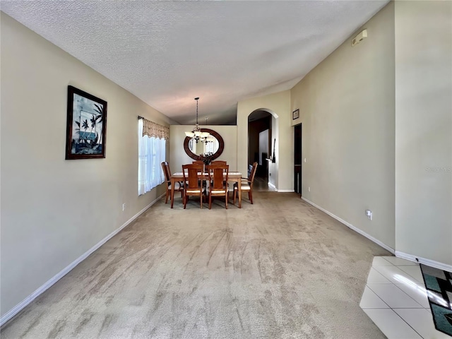 unfurnished dining area with arched walkways, baseboards, carpet, a textured ceiling, and a chandelier