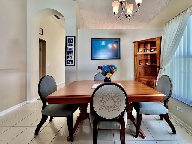 dining area with a textured ceiling, light tile patterned flooring, baseboards, and a notable chandelier