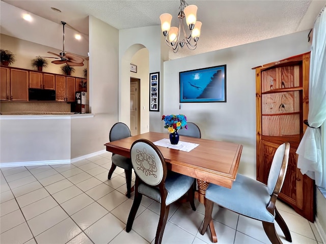 dining space with light tile patterned floors, baseboards, arched walkways, a textured ceiling, and ceiling fan with notable chandelier