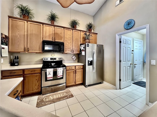 kitchen featuring light tile patterned floors, stainless steel appliances, light countertops, a ceiling fan, and brown cabinetry