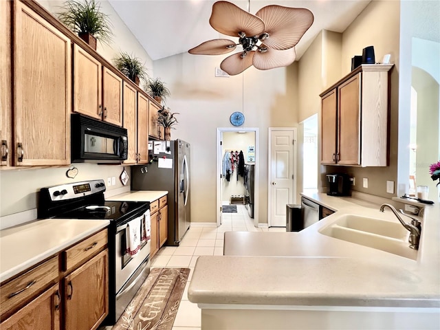 kitchen with stainless steel appliances, light countertops, a ceiling fan, light tile patterned flooring, and a sink