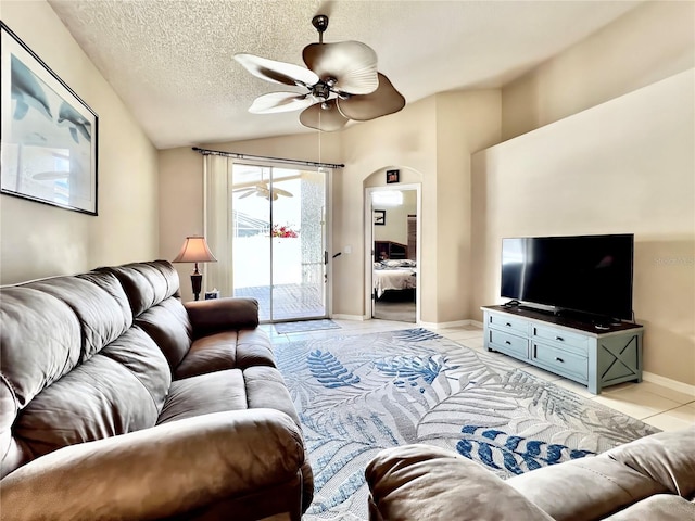 living room featuring light tile patterned floors, a textured ceiling, a ceiling fan, baseboards, and vaulted ceiling