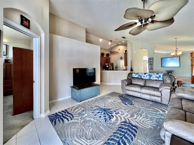 living room with light tile patterned floors, vaulted ceiling, a textured ceiling, baseboards, and ceiling fan with notable chandelier