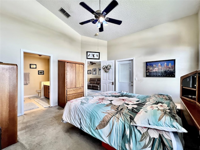 bedroom with carpet floors, visible vents, vaulted ceiling, a textured ceiling, and ensuite bath